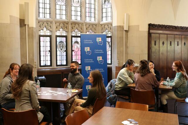Yale staff members in conversation, seated at tables